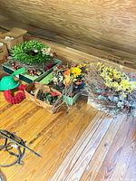 Group of wreaths, baskets and boxes of faux flowers on attic floor