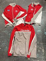 All three apparel pieces laid out: full-zip jacket, sleeveless vest, pullover