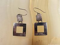 Front view showing both sterling earrings with open square drops and textured connectors