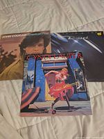 Front covers of all three LPs laid out on bed