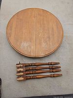 Round wooden table top, drop-leaf seam visible, surface wear