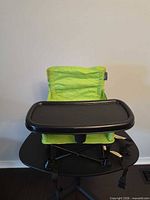 Front view of lime green hook-on high chair with black tray attached