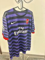 Front view of Nike Arsenal purple/black striped jersey on hanger