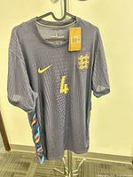 Front view showing Nike logo, England crest, number 4, tags, color and texture