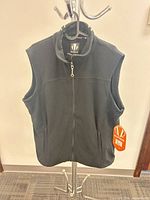 Front view of black Sunice fleece vest hanging, tags attached