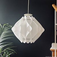 Full view of hanging white sculptural Zicoli pendant lamp against dark wall