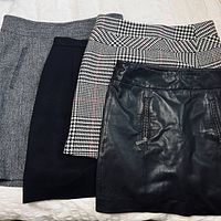 Four skirts overlapped showing leather, houndstooth, tweed, and plain black fabric