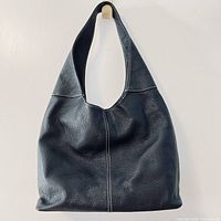 Front view of navy blue pebbled leather satchel purse hanging to show shape and strap