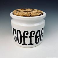 Front view of white ceramic coffee canister with cork lid and black lettering