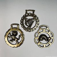 Front view of three brass horse brasses showing designs