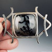 Front view of sterling brooch in hand highlighting dendritic agate and openwork frame