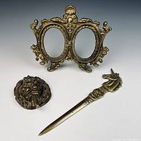 Overview of all three brass items: double photo frame, lion knocker, unicorn letter opener