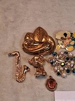 Group shot showing leaf brooch, saxophone pin, dog brooch, floral spray brooch, cameo, partial cat brooch