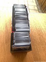 Tall stack of Pokémon cards inside open cardboard deck box