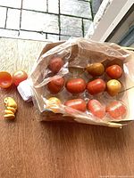 Box containing multiple orange and yellow plastic Kinder Surprise capsules plus empty halves and one toy outside