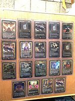 Fronts of 18 sleeved gilded foil cards displayed on board