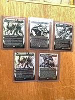 All five sleeved cards displayed on wood surface: two Evolved Spinoderm, Skrelv, Melira, Kethek