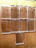 Nine clear Ultra Pro magnetic card cases displayed on wood backdrop