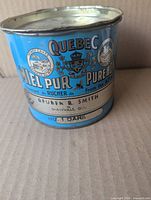 Front view of blue Quebec Pure Honey 2-lb tin showing main graphics and text