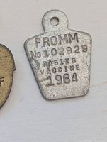 Close-up of Fromm 1964 rabies vaccine tag
