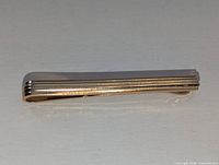 front view of gold-tone tie bar showing ridged design