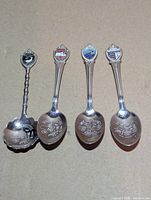 All four silver plated souvenir spoons front view