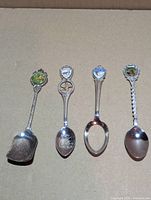 Four souvenir spoons laid out showing fronts