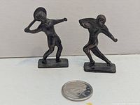 Front view of both bronze-finish sports figures with quarter for scale