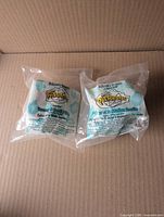 Front view of two unopened McDonald’s Flintstones Happy Meal toys