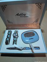 Open gift box showing watch, bracelet, calculator and pen arranged in foam insert