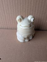 Front view of white milk glass frog-shaped bottle