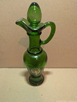 Full view of Avon Nile Green glass bath oil decanter with stopper, handle, spout and gold emblem