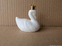 Front view of white milk glass swan perfume bottle with gold crown cap