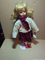 Front view of porcelain doll on stand showing outfit and attached tag