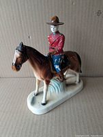 Full view of ceramic RCMP officer on horse from left side showing overall form and paint wear