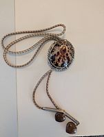 Full view of bolo tie showing shell centerpiece, cord and tips