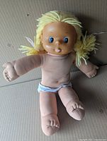 Front view of doll showing face, vinyl limbs, cloth body, diaper