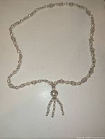 Full view of faux pearl and silver-tone beaded necklace showing tassel and bead pattern