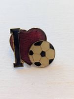 Front view of enamel lapel pin showing I, heart, soccer ball design