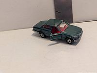 Front left view showing metallic green body, red interior and open driver door