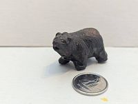 front angled view of small bronze-finish bear figurine beside a Canadian dime for scale