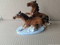 Side view of two running horse figurine on oval base