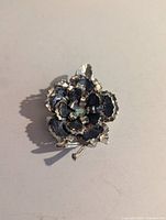 Front view of silver-tone flower brooch showing black enamel petals and rhinestone center