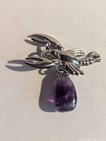 Front view of silver-tone lobster brooch with amethyst charm