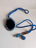 Entire bolo tie showing geode centerpiece, cord, and agate tips