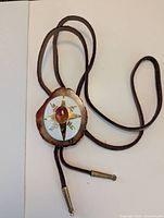 Full view of bolo tie showing leather cord, agate slice slide, and metal tips