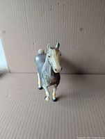 Front view of molded plastic horse figurine standing on cardboard background