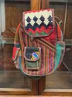 Front view of multicolour patchwork kilim backpack showing main body, front flap pocket and side pocket