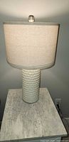 First lamp showing textured ceramic base and beige drum shade