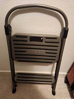 Front view of folded Cosco two-step stool showing brand name and step treads